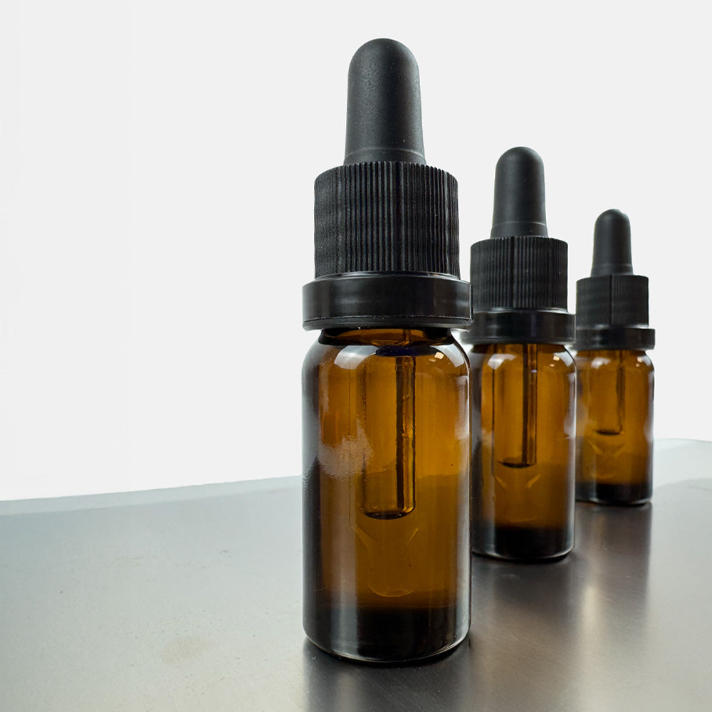 Flacons d'huile au CBD marque blanche en rangées sur une table