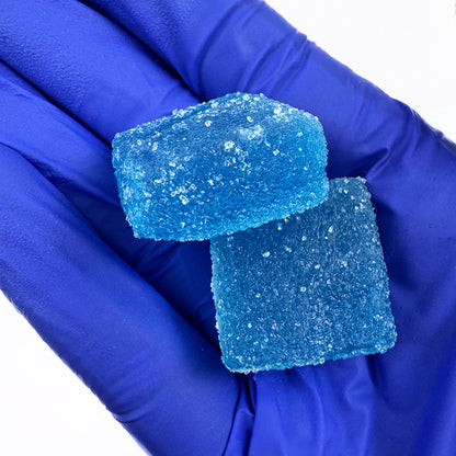 Deux gummies au THC bleu goûts myrtille tenus dans une main