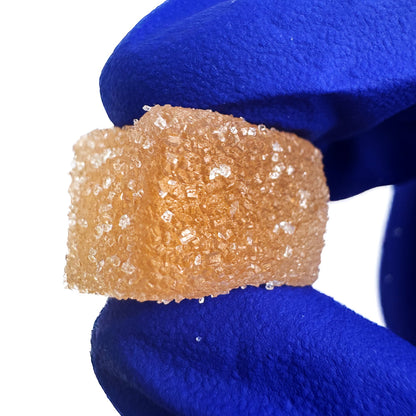 Main qui tient un gummies au THC orange